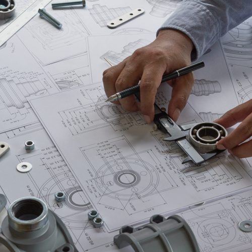 Engineer technician designing drawings mechanical parts engineering Engine
manufacturing factory Industry Industrial work project blueprints measuring bearings caliper tools